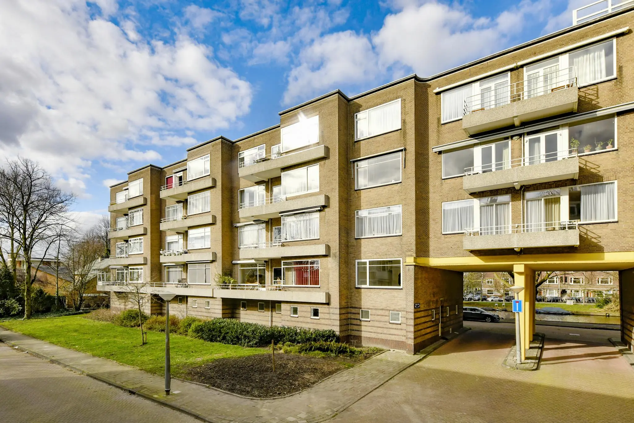 Appartementencomplex aan de Cornelis Dopperkade met bakstenen gevel, balkons en onderdoorgang bij zonnig weer.